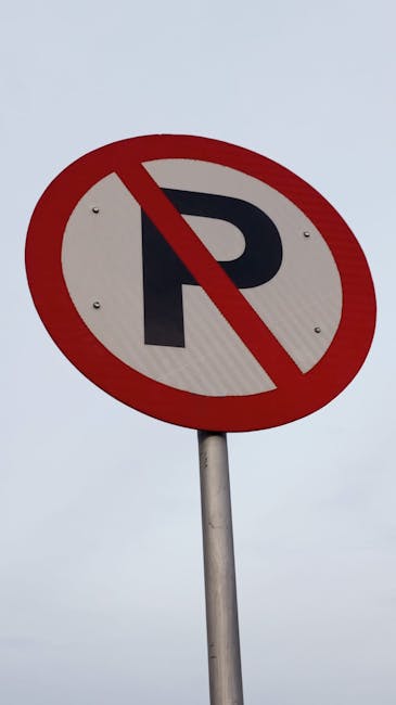 A blue, cubic parking sign mounted on a tall metal pole displays the letter 'P' accompanied by the number '3' on all visible sides. The sign is located outdoors against a clear, light blue sky with a